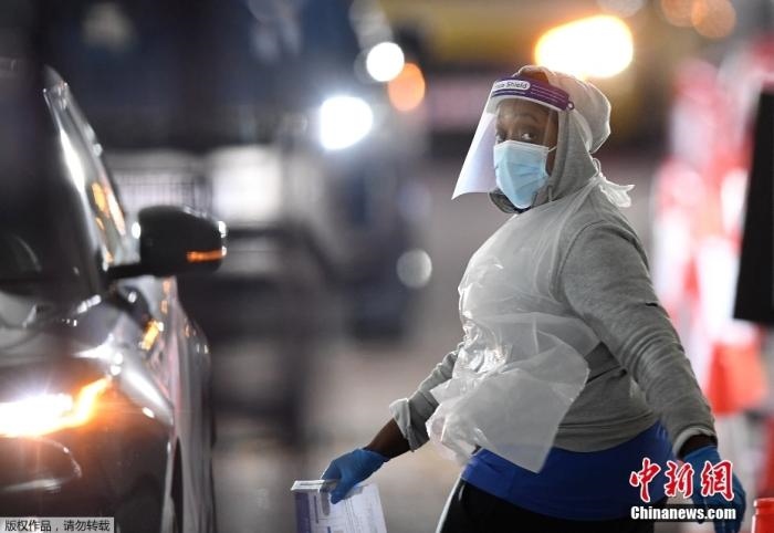 當(dāng)?shù)貢r(shí)間12月18日，英國政府公布的數(shù)據(jù)顯示，當(dāng)天英國新增奧密克戎毒株感染病例10059例。鑒于奧密克戎毒株感染病例激增，住院人數(shù)不斷上升，倫敦市長宣布倫敦進(jìn)入“重大事故”狀態(tài)。圖為倫敦的一個(gè)免下車檢測中心，一名醫(yī)務(wù)工作者正準(zhǔn)備對(duì)司機(jī)進(jìn)行核酸檢測。