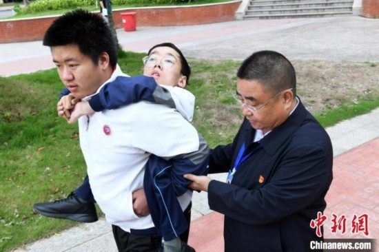 朱金祥背著鐘華強(qiáng)去教室上課的路上，也經(jīng)常碰到值班的校領(lǐng)導(dǎo)和老師前來(lái)搭把手。 卓忠偉 攝