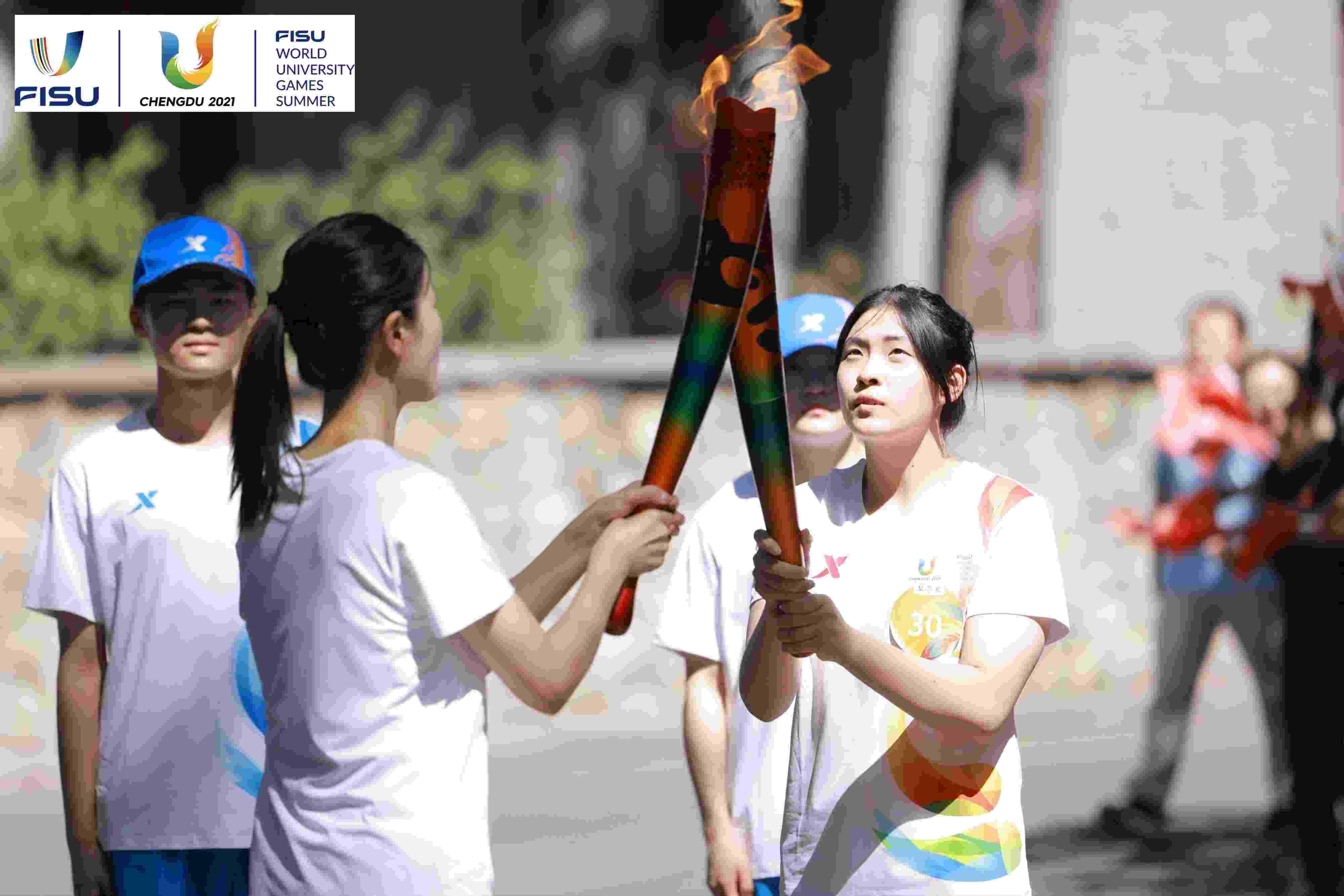 兩名大運會火炬手進行火炬?zhèn)鬟f。 圖片來源：成都大運會執(zhí)委會供圖