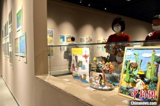 圖為家長(zhǎng)帶著孩子參觀展覽。呂明 攝