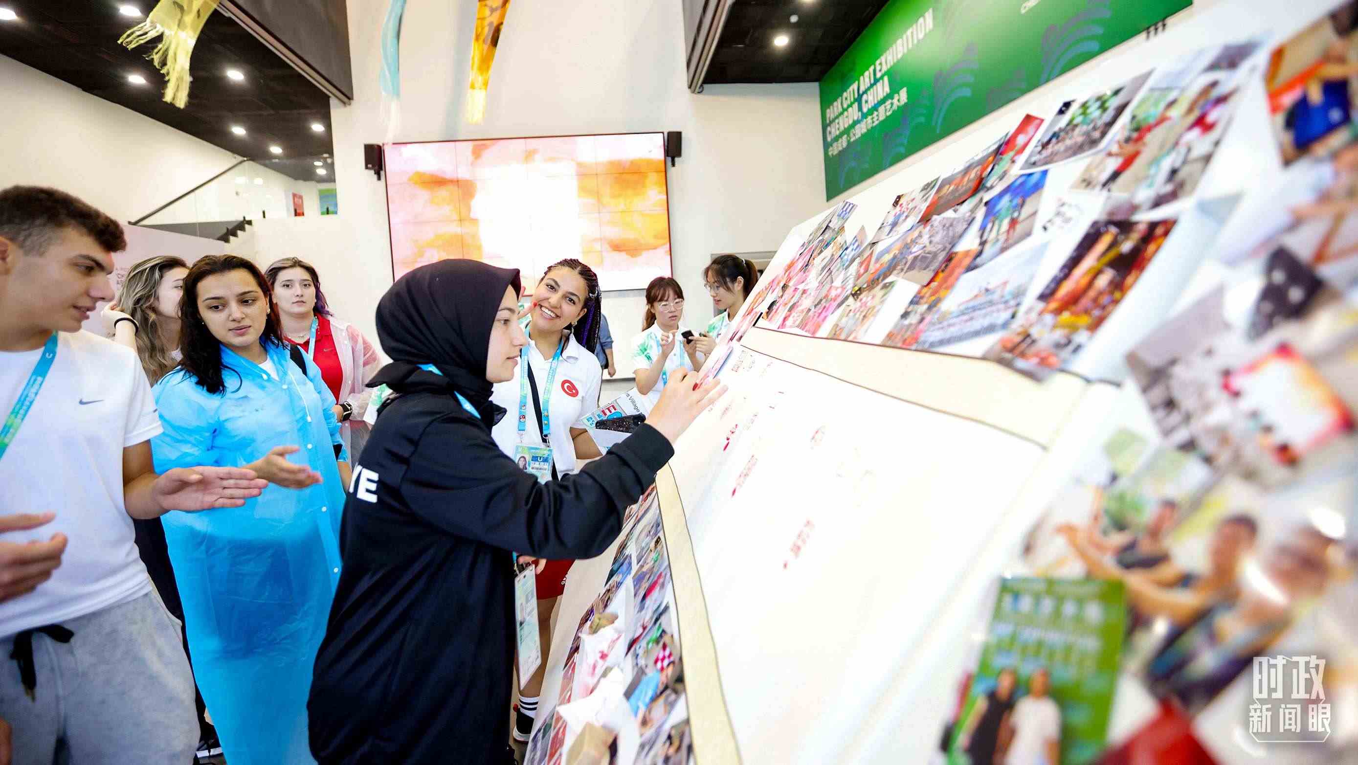 各國青年運(yùn)動(dòng)員正在參觀成都大運(yùn)村內(nèi)的“雪山下的公園城市，煙火里的幸福成都”主題藝術(shù)展。（總臺央視記者魏幫軍拍攝）