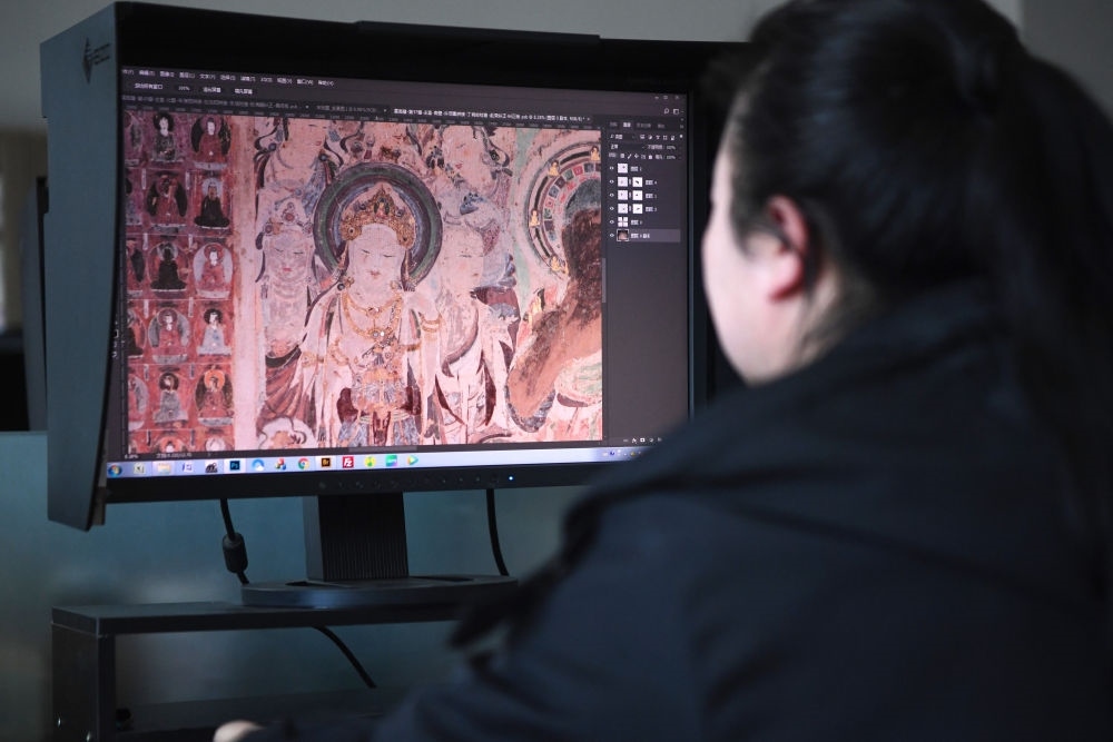 敦煌研究院文物數(shù)字化保護(hù)團(tuán)隊圖像處理人員年海麗在拼接壁畫圖像（2023年4月25日攝）。數(shù)字化探索為莫高窟的保護(hù)與傳承開辟了全新路徑，數(shù)字技術(shù)讓敦煌文物走出洞窟，跨出國門，走向“永久保存、永續(xù)利用”。新華社記者 陳斌 攝