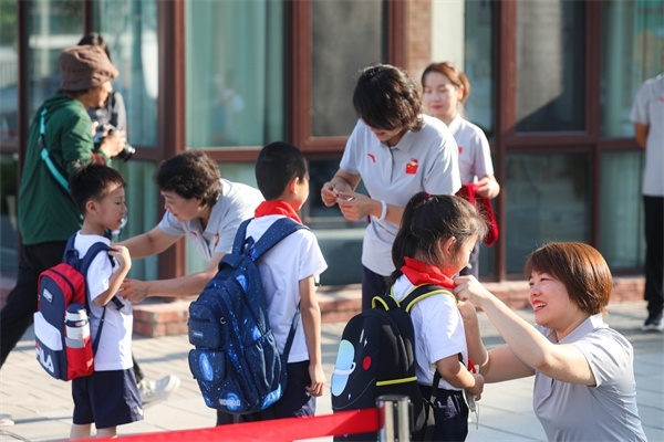 8月30日，雄安史家胡同小學(xué)學(xué)生體驗(yàn)學(xué)校生活。老師為學(xué)生佩戴?；?。