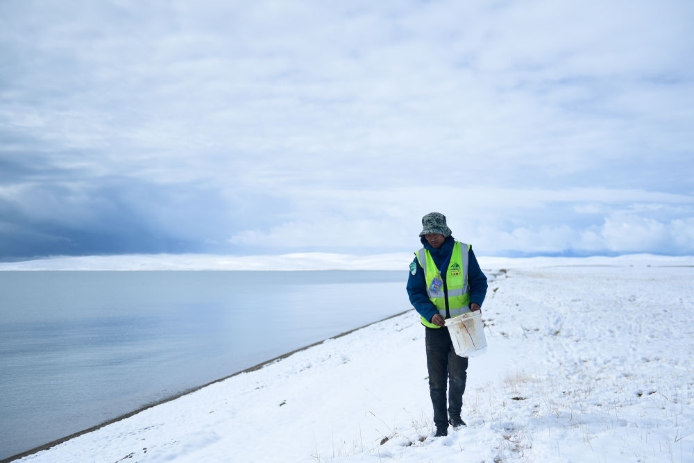 2021年10月20日，在青海省果洛藏族自治州瑪多縣扎陵湖鄉(xiāng)勒那村，三江源國(guó)家公園黃河源園區(qū)生態(tài)管護(hù)員在扎陵湖邊撿拾垃圾。新華社記者 張龍 攝