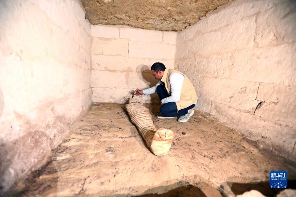 10月15日，在埃及明亞省考古現(xiàn)場(chǎng)，考古人員清理一座石鑿墓中的木乃伊。新華社發(fā)（艾哈邁德·戈馬攝）