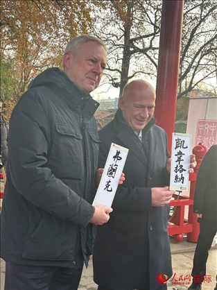 柏林市長韋格納（右）、動物園監(jiān)事會主席布魯克曼（左）手持中國文化中心工作人員現(xiàn)場手書的中文名字。人民網(wǎng)記者 徐馨攝