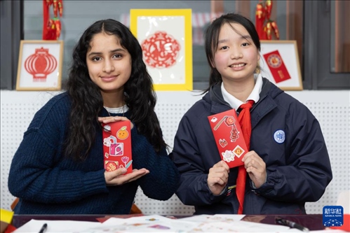 1月28日，美國馬斯卡廷中學(xué)學(xué)生（左）和復(fù)旦大學(xué)第二附屬學(xué)校學(xué)生展示互相送出的寫有寄語祝福的紅包。 新華社記者 王翔 攝