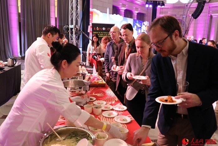 當?shù)貢r間3月7日晚，華盛頓聯(lián)合車站廣場舉行駐美使團“使館主廚挑戰(zhàn)賽”。圖為當?shù)孛癖娫谥袊古_前體驗中國美食。人民網(wǎng)記者 李志偉攝