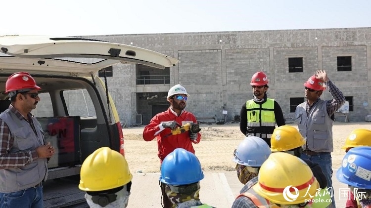 穆薩瓦爾(圖中紅衣人）現(xiàn)場演示工具操作規(guī)范。人民網(wǎng)記者 管克江攝