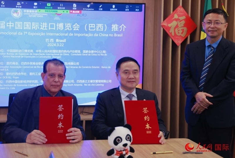 巴西外貿(mào)商會聯(lián)合會會長阿代爾·羅伯托（左）與中國國際進口博覽局副局長吳政平（中）現(xiàn)場簽訂協(xié)議。人民網(wǎng)記者 宋亦然攝
