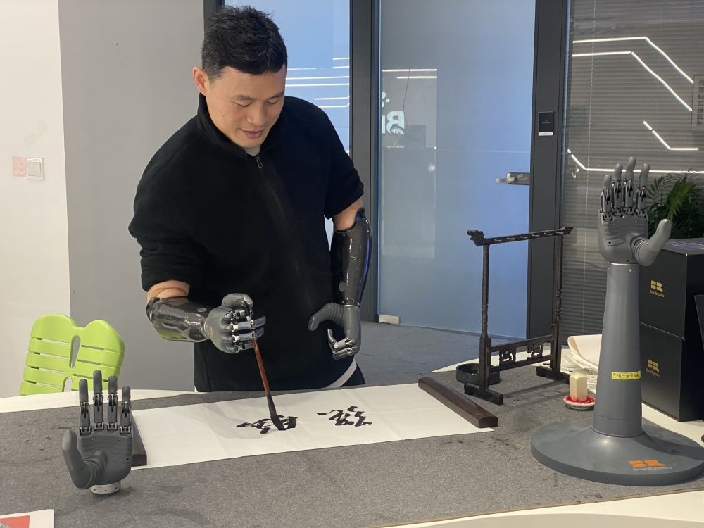 2024年3月29日，在浙江強(qiáng)腦科技有限公司展廳內(nèi)，失去雙手的產(chǎn)品體驗(yàn)官倪敏成依靠智能仿生手寫毛筆字。新華社記者 魏一駿 攝