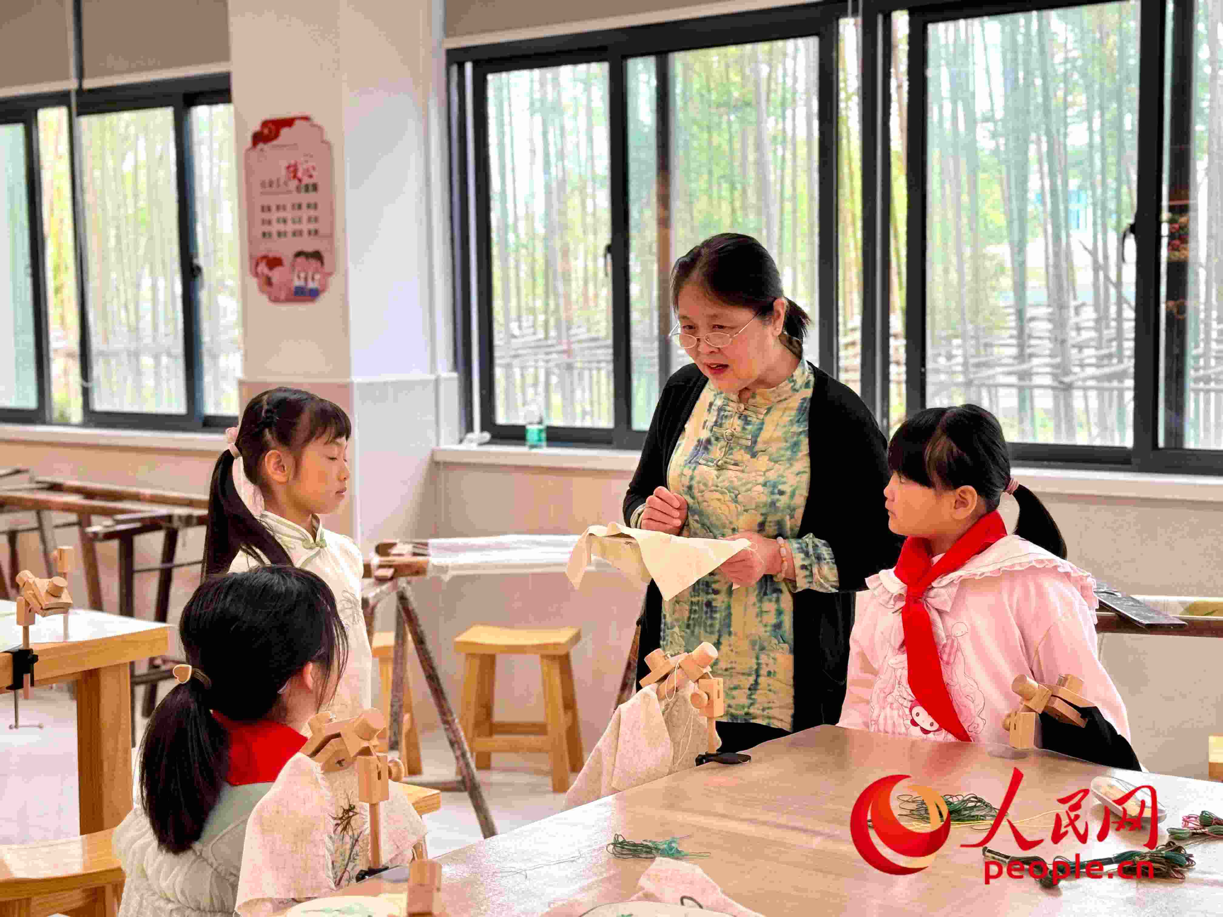 顧建珍（左三）在教孩子們刺繡知識。人民網(wǎng) 周靜圓攝