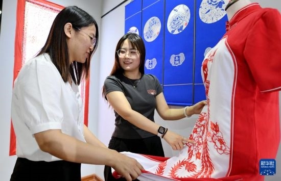 5月31日，在衡水市阜城縣一家剪紙工作室，游客在觀賞帶有剪紙?jiān)氐钠炫邸? width=