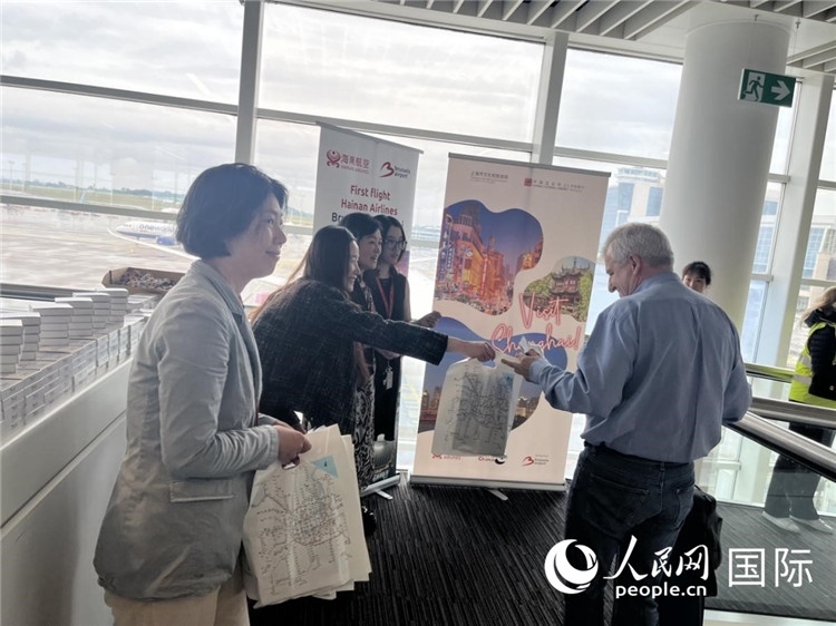 圖為工作人員向乘客發(fā)放復航首班禮物。 牛瑞飛攝