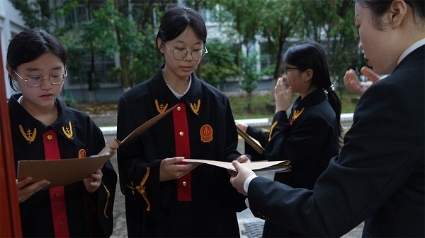 圖①：武平法院干警向?qū)W生分發(fā)道具卷宗。