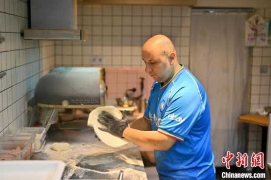 近日，韋榮耀在自家披薩小店內忙活。俞靖 攝