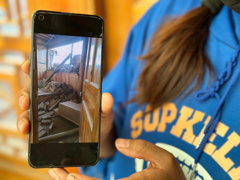 圖為7月17日拉毛東智在手機(jī)上找出地震后房屋受損的照片。新華社記者 張子琪 攝