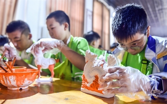 小朋友們?cè)诼尻柺忻辖騾^(qū)朝陽鎮(zhèn)南石山村體驗(yàn)唐三彩素胎施釉技藝。圖片來源：視覺中國