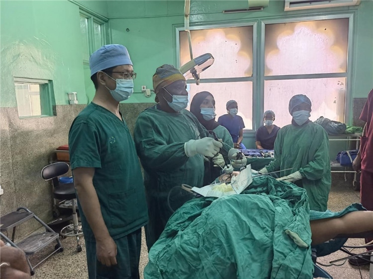 隊長蔣國慶（左一）關注當地醫(yī)生手術情況。中國援桑醫(yī)療隊供圖