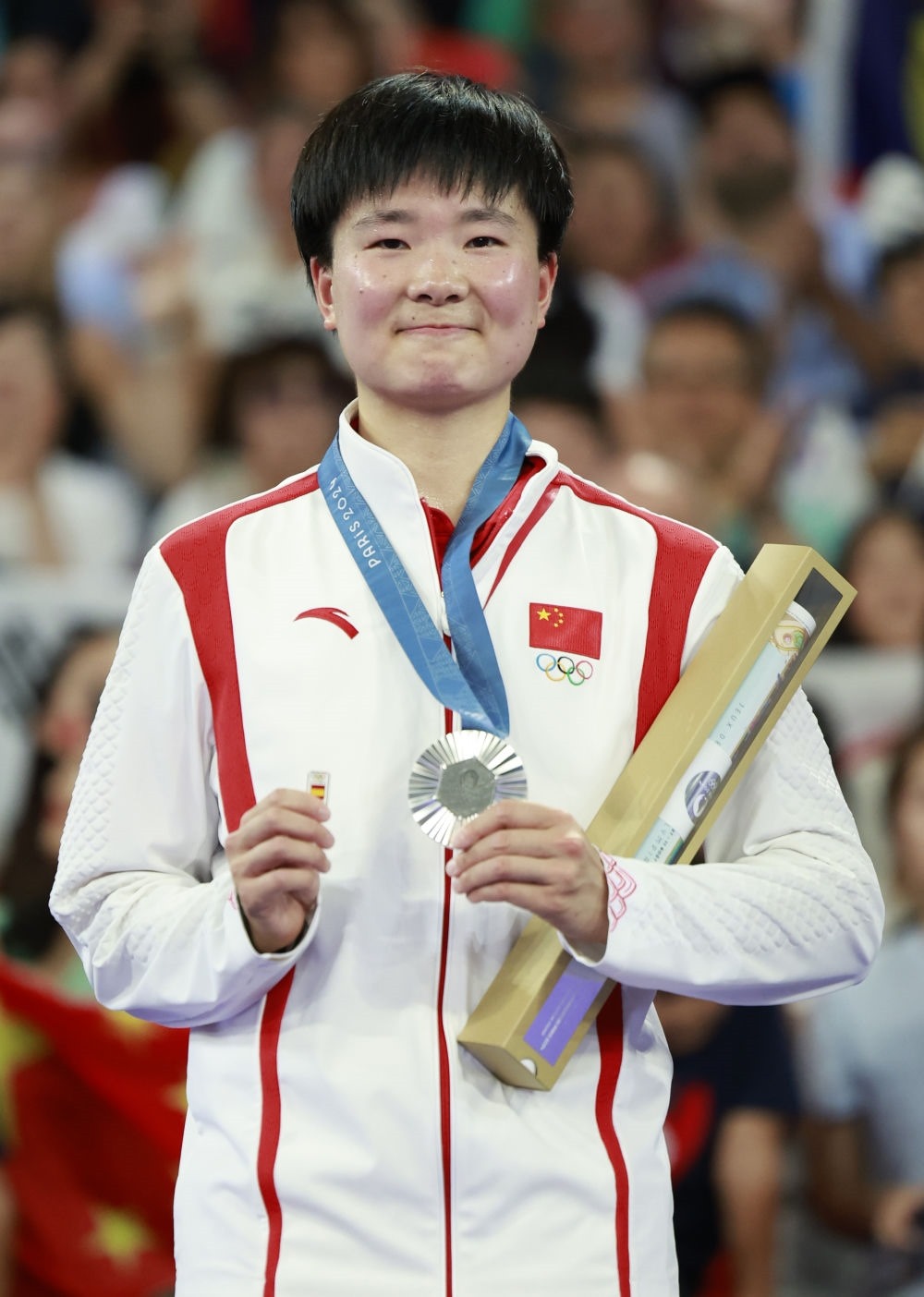 巴黎奧運會羽毛球女子單打亞軍、中國選手何冰嬌在頒獎儀式上一手握著銀牌，一手握著西班牙奧委會徽章（2024年8月5日攝）。新華社記者 任正來 攝