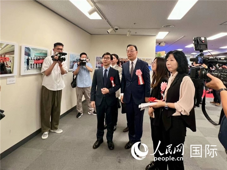 中國(guó)國(guó)際航空日韓地區(qū)支社支社長(zhǎng)馮力為中國(guó)駐日本大使館臨時(shí)代辦施泳等嘉賓介紹展出圖片。人民網(wǎng) 許可攝