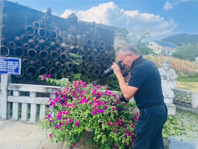 遠(yuǎn)處黔北民居錯落有致，近處一只黑色的蝴蝶穿梭于粉紫色三角梅花叢間隙，與俄羅斯“大歐亞”總編輯弗拉基米爾·別列日內(nèi)赫的鏡頭玩起了捉迷藏，“你追我逃，不亦樂乎”。（張亞欣攝）