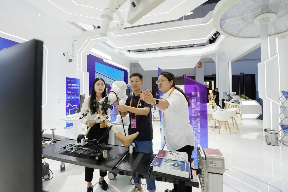 9月11日，一位媒體記者（中）在2024年服貿(mào)會國家會議中心會場體驗北京納通科技集團有限公司的膝關(guān)節(jié)置換手術(shù)機器人。新華社記者鞠煥宗 攝