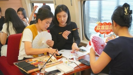 10月1日，旅客們在G1634次列車上給油紙傘作畫。新華社記者周義 攝
