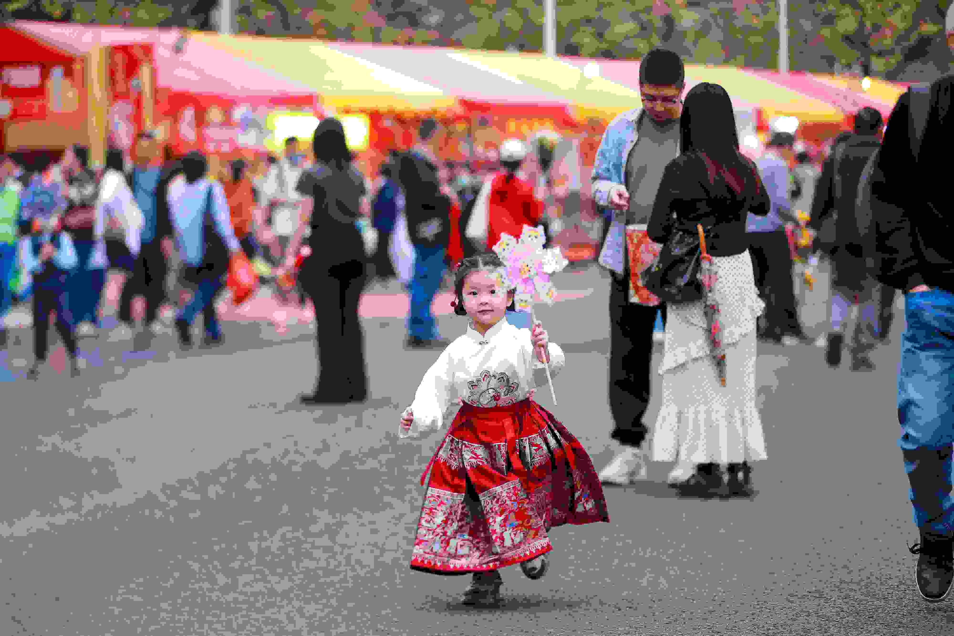 拿著風(fēng)車穿著馬面裙的小女孩在廣州的花市上開心奔跑。