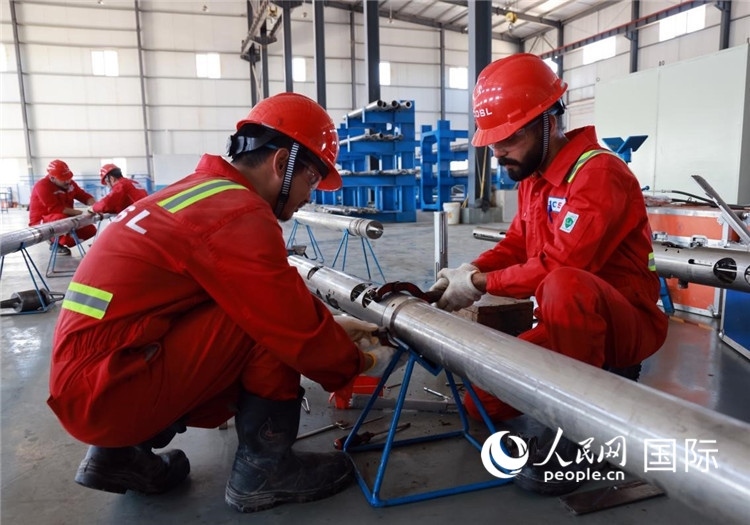 中伊員工共同在檢修鉆井設備。人民網(wǎng)記者管克江攝