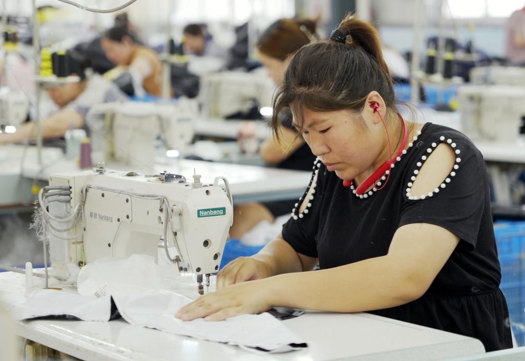 5月20日，村民在李寨村服裝加工廠內(nèi)忙碌。河南省周口市沈丘縣馮營鎮(zhèn)李寨村地處豫東平原。近年來，乘著脫貧攻堅與鄉(xiāng)村振興政策的東風(fēng)，李寨村積極探索產(chǎn)業(yè)發(fā)展模式，通過“龍頭企業(yè)+村集體經(jīng)濟(jì)+農(nóng)戶”的方式，逐漸發(fā)展形成肉牛養(yǎng)殖、設(shè)施農(nóng)業(yè)、服裝加工、康養(yǎng)民宿等產(chǎn)業(yè)，以產(chǎn)業(yè)振興助力鄉(xiāng)村振興。新華社記者 李嘉南 攝