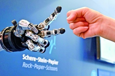 在德國漢諾威工博會上，參觀者與一款智能機(jī)器人進(jìn)行“石頭剪子布”游戲。新華社發(fā)