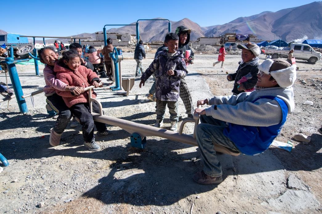 1月11日，在定日縣措果鄉(xiāng)塘仁村安置點，西藏星光社會工作服務中心志愿者和孩子們一起玩耍，進行災后心理疏導。人民網(wǎng)記者 翁奇羽攝