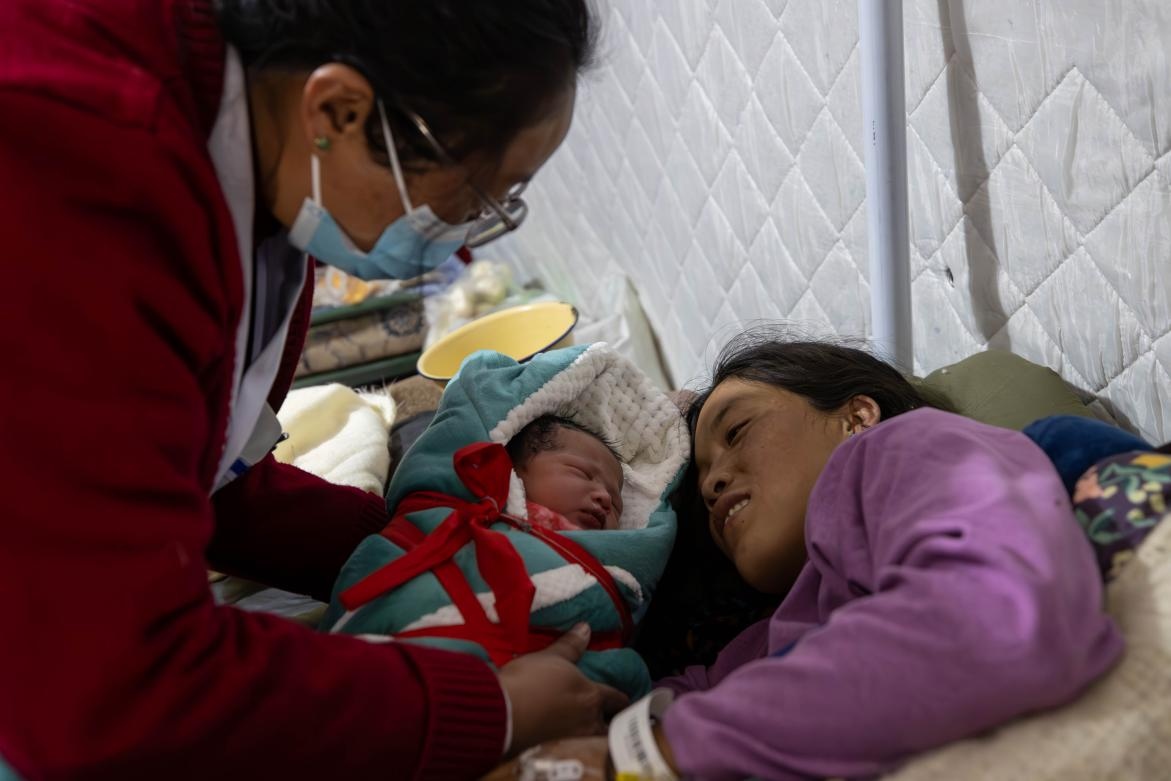 1月10日，定日縣中心醫(yī)院的婦產科醫(yī)生悉心照看一位母親和她懷里的新生兒。人民日報記者張武軍攝