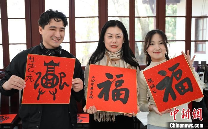 1月20日，外籍留學(xué)生和西泠印社社員李硯(中)展示各自創(chuàng)作的福貼。當(dāng)日，來自巴西、馬來西亞、加納、哈薩克斯坦的外籍留學(xué)生在浙江杭州西泠印社體驗(yàn)福貼、春聯(lián)和篆刻，感受古老的中國(guó)傳統(tǒng)文化。中新社記者 王剛 攝