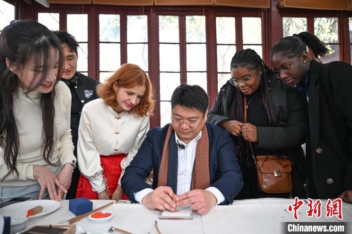 1月20日，篆刻家王臻向外籍留學(xué)生展示篆刻印章。當(dāng)日，來自巴西、馬來西亞、加納、哈薩克斯坦的外籍留學(xué)生在浙江杭州西泠印社體驗(yàn)福貼、春聯(lián)和篆刻，感受古老的中國(guó)傳統(tǒng)文化。中新社記者 王剛 攝