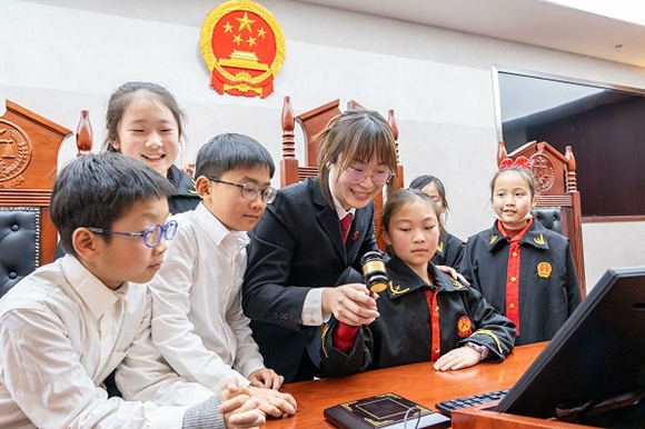 圖①：干警帶同學(xué)們體驗(yàn)敲法槌。