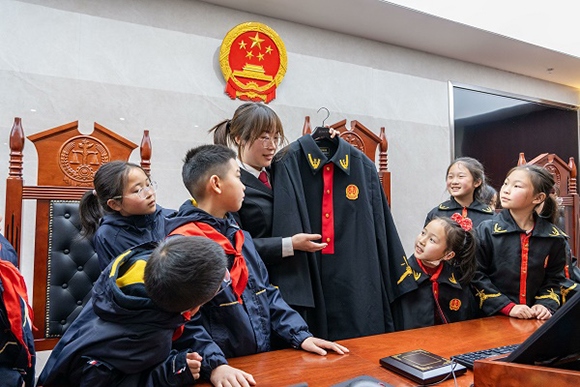 圖②：干警向同學(xué)們介紹法袍。