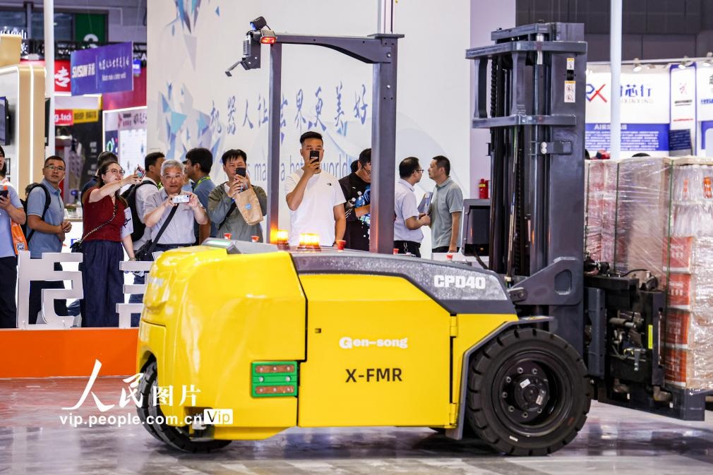 第24屆中國工博會現(xiàn)場，觀眾觀看叉取機器人作業(yè)演示。王初攝（人民圖片網(wǎng)）