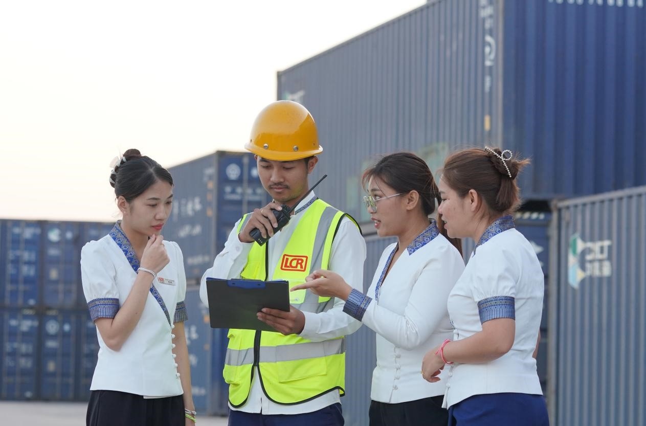 萬象南站貨運值班員陳尼啦（左一）與同事在一起討論工作。老中鐵路有限公司供圖