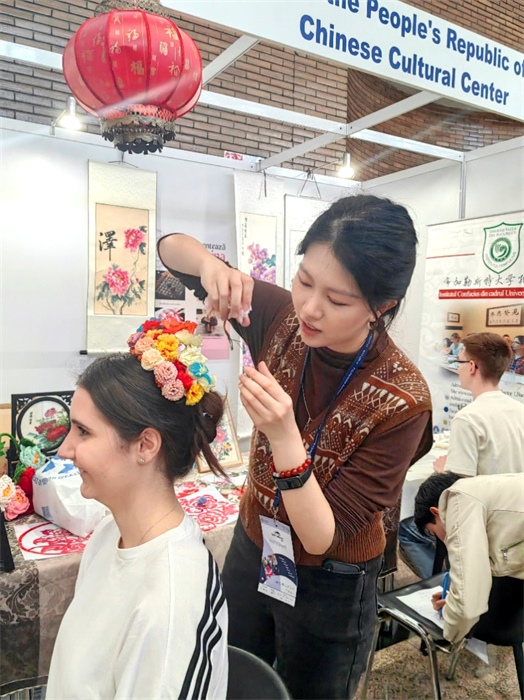 展覽正值羅馬尼亞迎春花節(jié)，國際中文教師志愿者潘婧穎向游客們介紹了國家非物質(zhì)文化遺產(chǎn)——福建泉州的簪花文化。布加勒斯特大學(xué)孔子學(xué)院供圖。