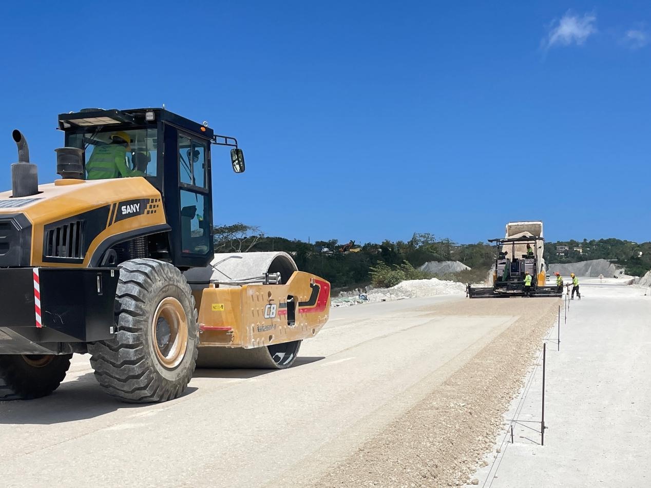 圖為中企承建的牙買加蒙特哥貝繞城路項(xiàng)目基層試驗(yàn)段正在進(jìn)行攤鋪和碾壓施工，相關(guān)施工工作已于日前順利完成。中國(guó)港灣美洲區(qū)域公司供圖
