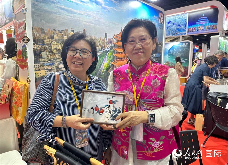 中國“大冶刺繡”傳承人劉小紅（右）參加泰國國際旅游展，向觀眾介紹中國非遺刺繡針法。人民網(wǎng)記者 簡承淵攝