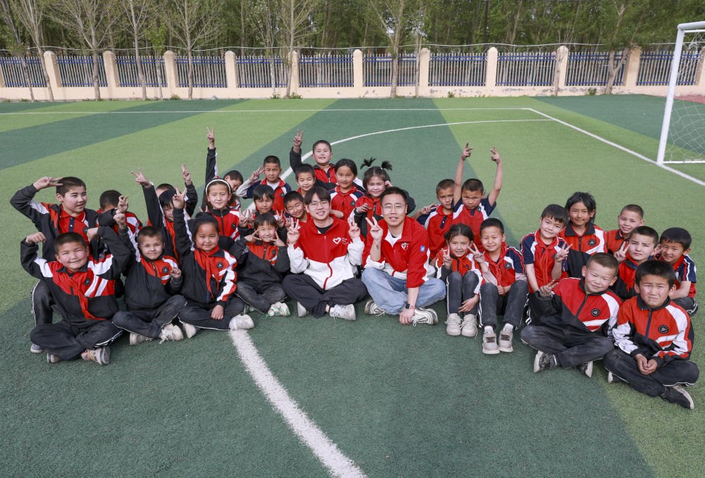 4月23日，在新疆克州阿圖什市哈拉峻鄉(xiāng)謝依特小學(xué)，支教教師王俊文（中左）、李軻凡（中右）和學(xué)生在一起。