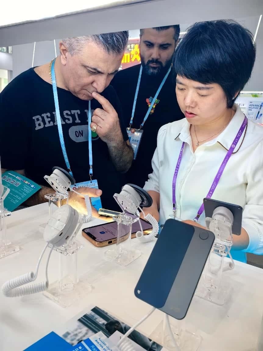 展臺工作人員向外商展示“AI TOP翻譯終端”。圖片來源：受訪者提供
